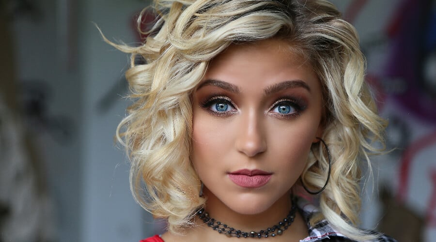 A girl with bleached blonde hair against a dark background